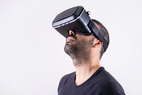 Young man using VR glasses headset looking up, portrait on light background Foto stock