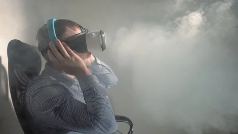 Young man using a VR headset and headphones, watching a video and listening to Stock Footage 101907970