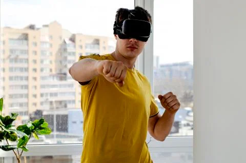 Young man using a VR headset to play fighting game. Portrait of a young man w Stock Photos