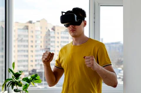 Young man using a VR headset to play fighting game. Portrait of a young man w Stock Photos