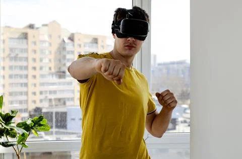 Young man using a VR headset to play fighting game. Portrait of a young man w Stock Photos