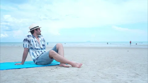 Young man on vacation on a white sandy beach, clear sky and sea Stock Footage 310117992