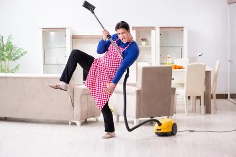 Young man vacuum cleaning his apartment Fotos Stock