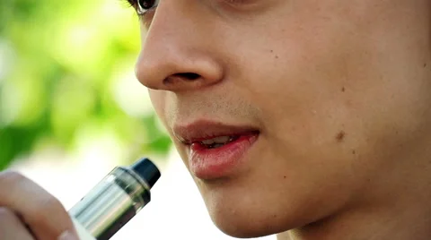 Young man vaping E-Cigarette in the park, close-up, slow motion 1 스톡 동영상 65759476
