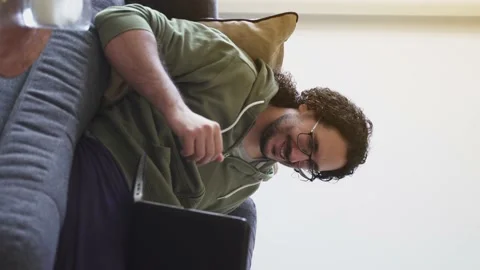 Young man in video call saying hello to laptop on the sofa Stock Footage 164906426