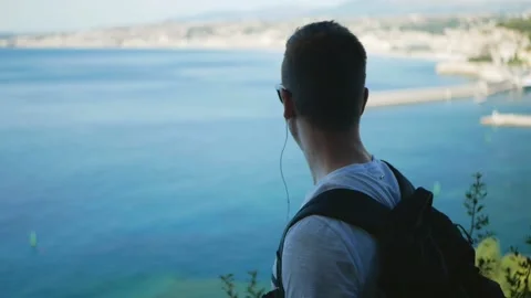 Young man at viewpoint looking at sea view slowmo Stock Footage 130415913