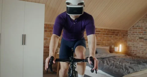 Young man in virtual reality glasses is exercising on an exercise bike, indoor Video stock 233776110