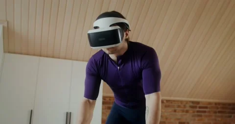 Young man in virtual reality glasses is exercising on an exercise bike, indoor Video stock 233776200