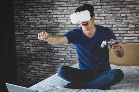 Young man in virtual reality headset or 3d glasses playing video game and poi Stock Photos