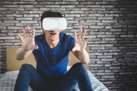 Young man in virtual reality headset or 3d glasses playing video game and poi Stock Photos