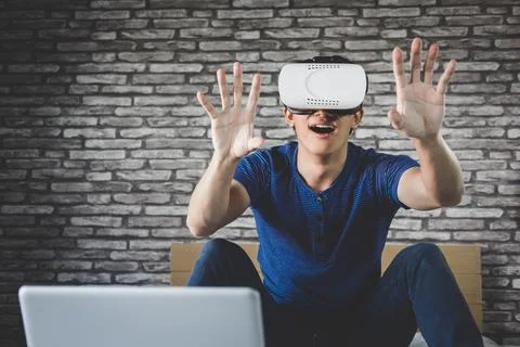 Young man in virtual reality headset or 3d glasses playing video game and p.. Stock Photos