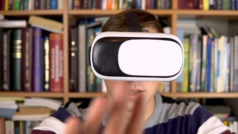Young man in VR glasses in the library. A man with a VR helmet on his head 스톡 동영상 121536031