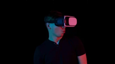 Young man in VR glasses. A man immersed in virtual reality makes movements with Stock Footage 123529520