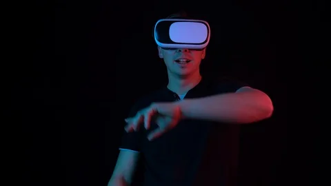 Young man in VR glasses. A man immersed in virtual reality makes movements with Stock Footage 123532056