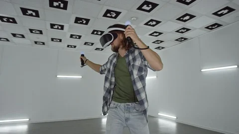 Young man in vr headset using controllers for a fighting videogame in an empty Stock Footage 125910204