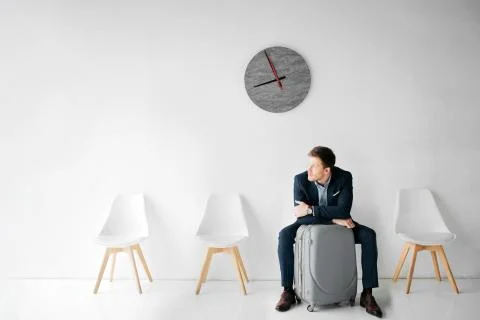 Young man wait for flight in room. He sit on chair and look to leaft. Guy lean Stock Photos