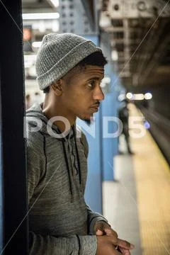 A young man waits for a train on a NYC subway platform. Stock Photos