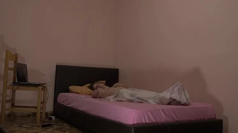 Young man wakes up to phone notification, sits up in bed to check phone. Stock Footage 108783232