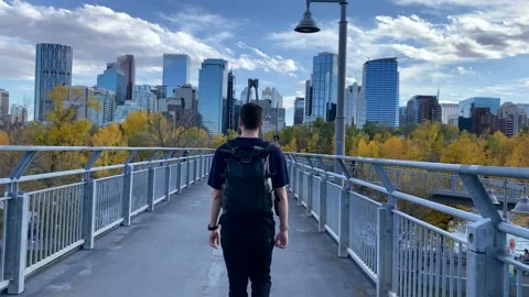 Young Man walking across Bow river bridge in Calgary Stock Footage 168918378