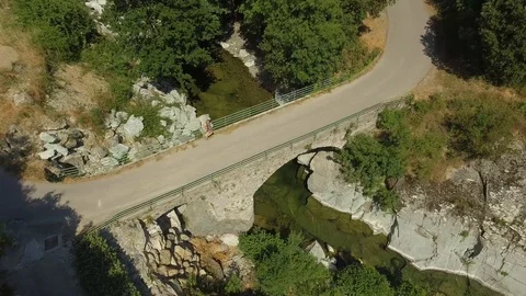 Young man walking across a bridge over a river and leaning on the fence, Corsica Stock Footage 85598164