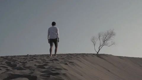 Young man walking alone on the desert Stock Footage