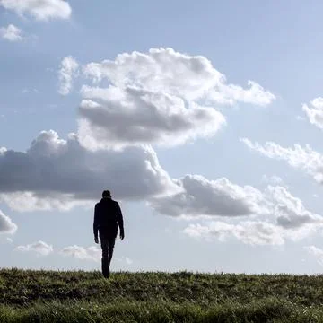 Young man walking alone in an empty field Stock-Fotos