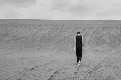 Young man walking alone on the sand in sandy desert Foto stock