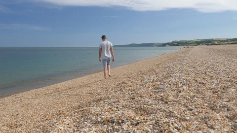 Young man walking along beach, admires the sea Stock Footage 77436377