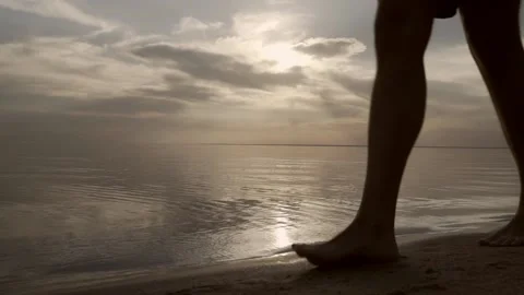 A young man walking along the beach at sunset. Stock Footage 156229079