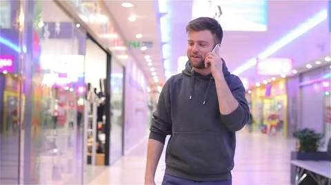 Young Man Walking and Talking on the Phone in a Mall. Stock Footage 47977325