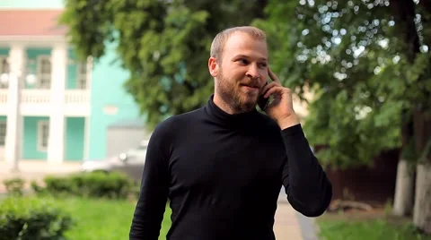The Young Man Walking and Talking on the Phone in the Park Stock Footage 50994892