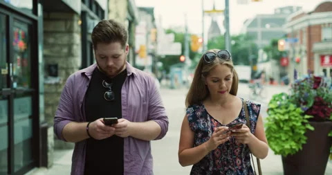 Young man walking and texting on his phone near busy street with soft day lighti Stock Footage 199463567