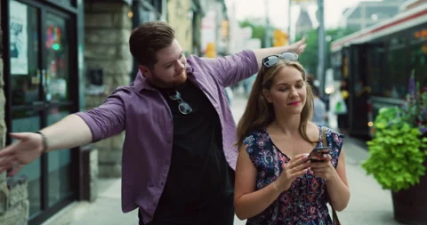 Young man walking and trying to get woman's attention as she checks her phone ne Video stock 199456756