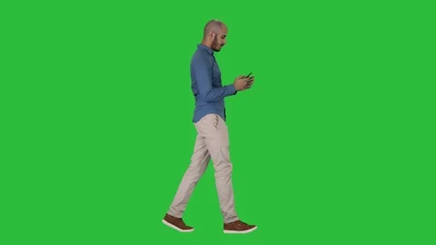 Young man walking and using a phone on a Green Screen, Chroma Key. Stock-Footage 108774713