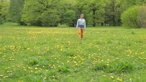 Young man is walking around the field with dandelions Video stock 76573970