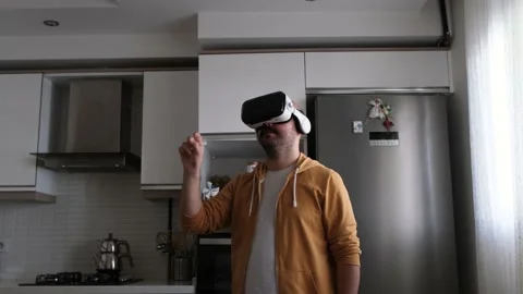 Young man walking around virtual market with vr glasses in kitchen. Vídeo Stock 162635784