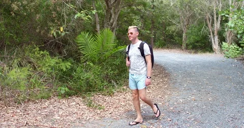 Young man walking with backpack in rainforest Stock Footage 87853658