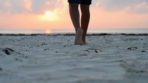 Young man walking barefoot on a sandy beach on the ocean, in the morning at Stock Footage 242559337