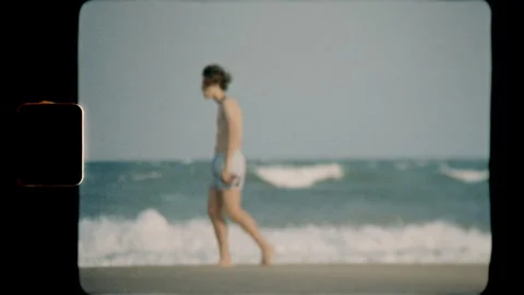 Young man walking on the beach captured on Super 8 film Stock Footage 345489468
