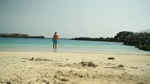 Young man walking on the beach HD Stock Footage 10894432