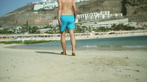 Young man walking on the beach HD Stock Footage 10901845