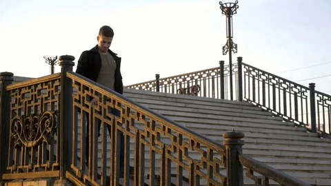 Young man walking on bridge and talk on phone sunset shot Stock Footage 80987216