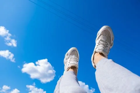 Young man walking in the clouds. Concept, white sneakers on a blue background Stock Photos