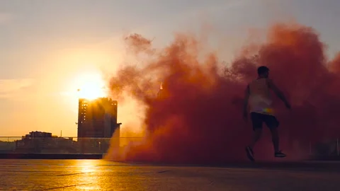 Young man walking with colored smoke at the street. Stock Footage 95596517