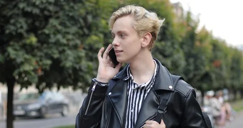 Young man walking down the street and talking emotionally on the phone. emotion Stock Footage 126576659