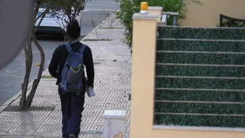 A young man walking down a street with backpack and leaflets, rear view Stock Footage 143002096