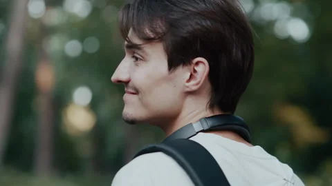 Young man walking in forest smiling with backpack and headphones outdoors 库存影片 339215349