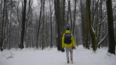 Young Man Walking In The Forest On The Snow In A Yellow Jacket With a Backpack Stock Footage 114080892