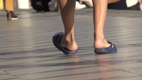 Young man walking with his plastic sandals Stock Footage 315165137