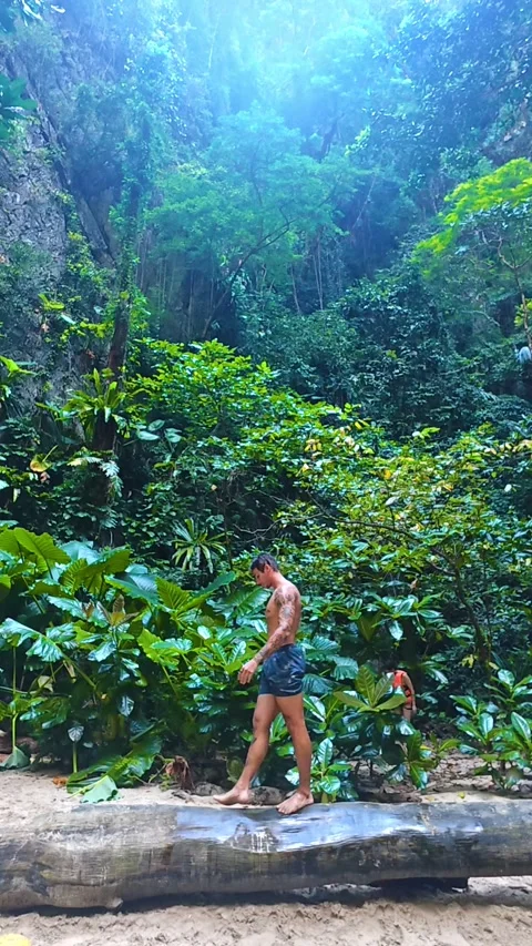 Young man walking on a log in tropical paradise in Thailand Vídeo Stock 334671927